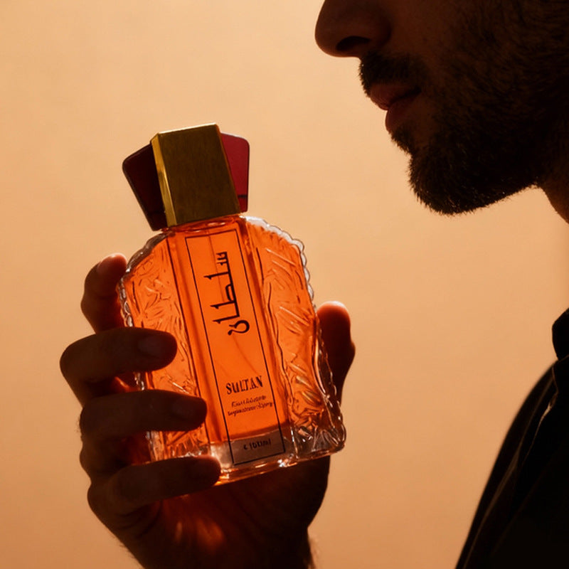 Bearded man holding the faceted Sultan eau de toilette bottle up in warm amber evening light