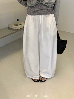 Model in white cotton wide leg trousers with drawstring waist and flat sandals