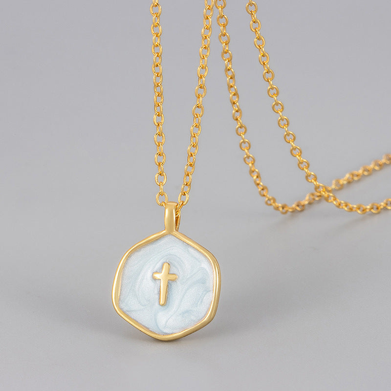 Pale blue enamel cross pendant on a gold tone chain, hexagon medallion with a slim raised gold cross at centre