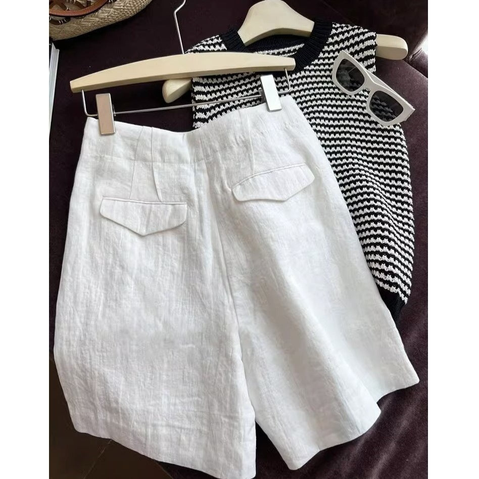 White high waist linen shorts hung beside a striped knit top and sunglasses