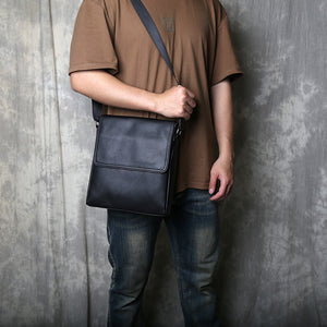 Front view of the black men's shoulder bag with its fold-over flap closed