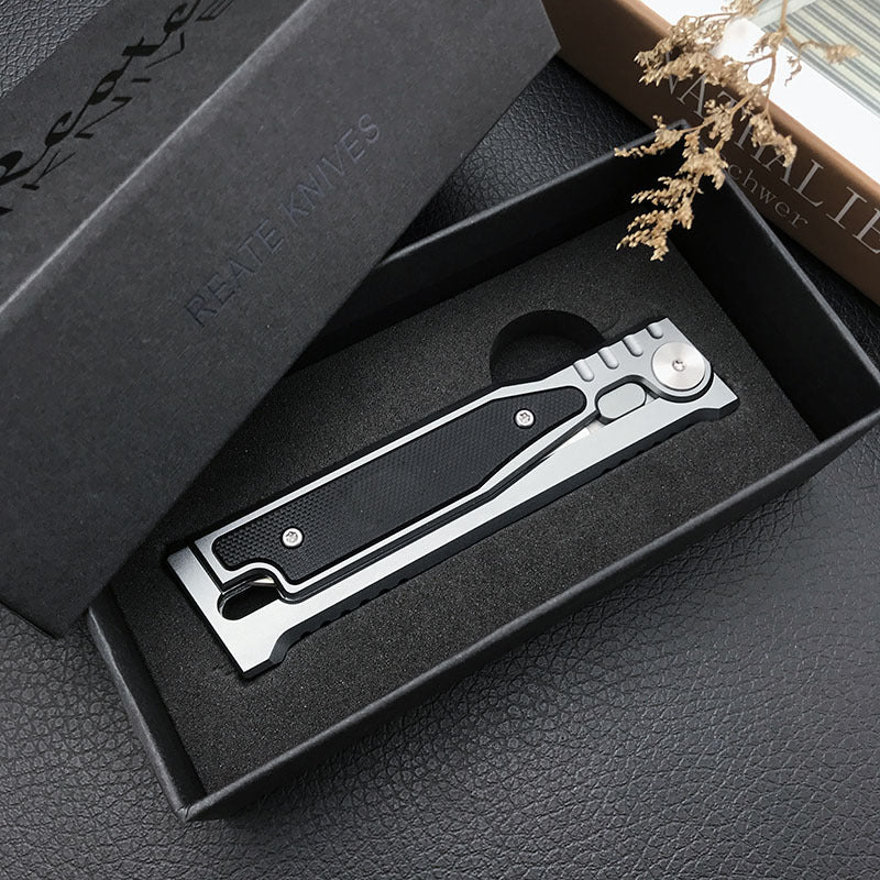 Closed folding pocket knife lying in an open black presentation box with a foam insert