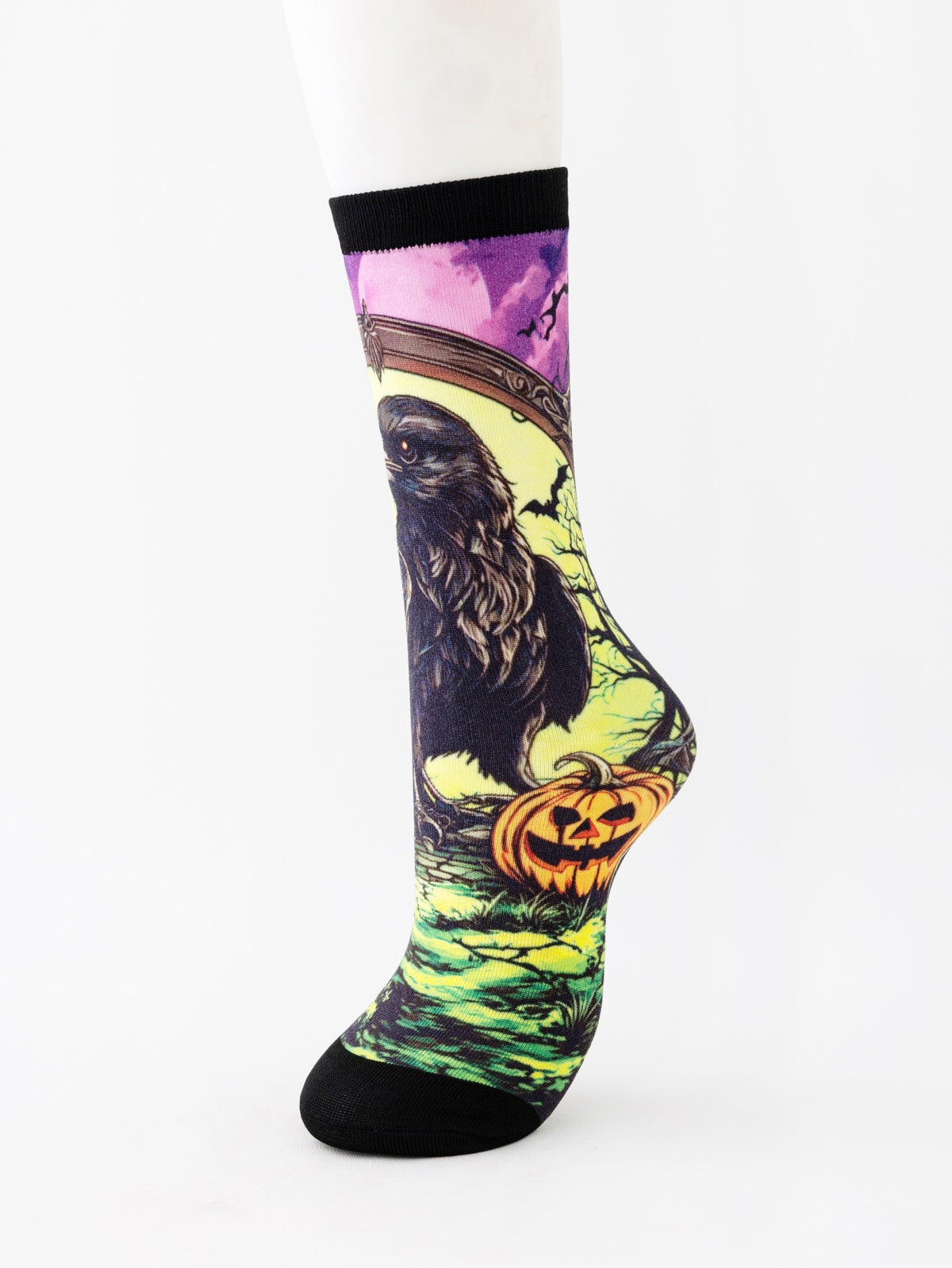 Mid-calf sock on a mannequin printed with a dark raven beside a glowing pumpkin on green and yellow