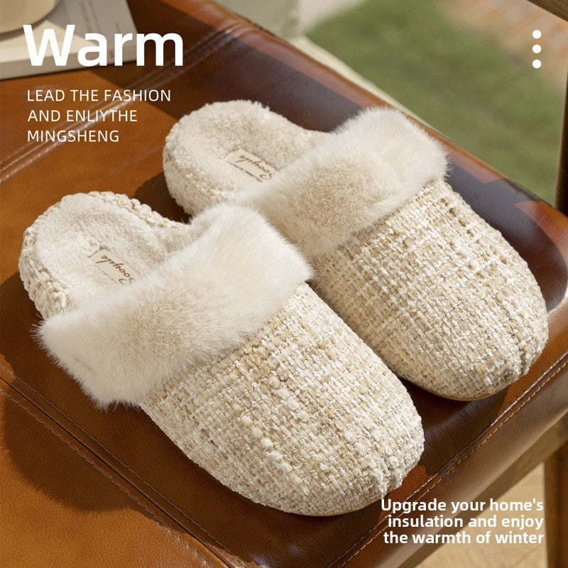 Pair of cream tweed look knit slippers with a plush faux fur cuff resting on a brown leather bench