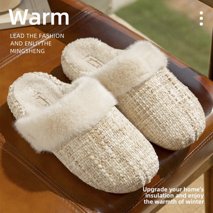 Pair of cream tweed look knit slippers with a plush faux fur cuff resting on a brown leather bench