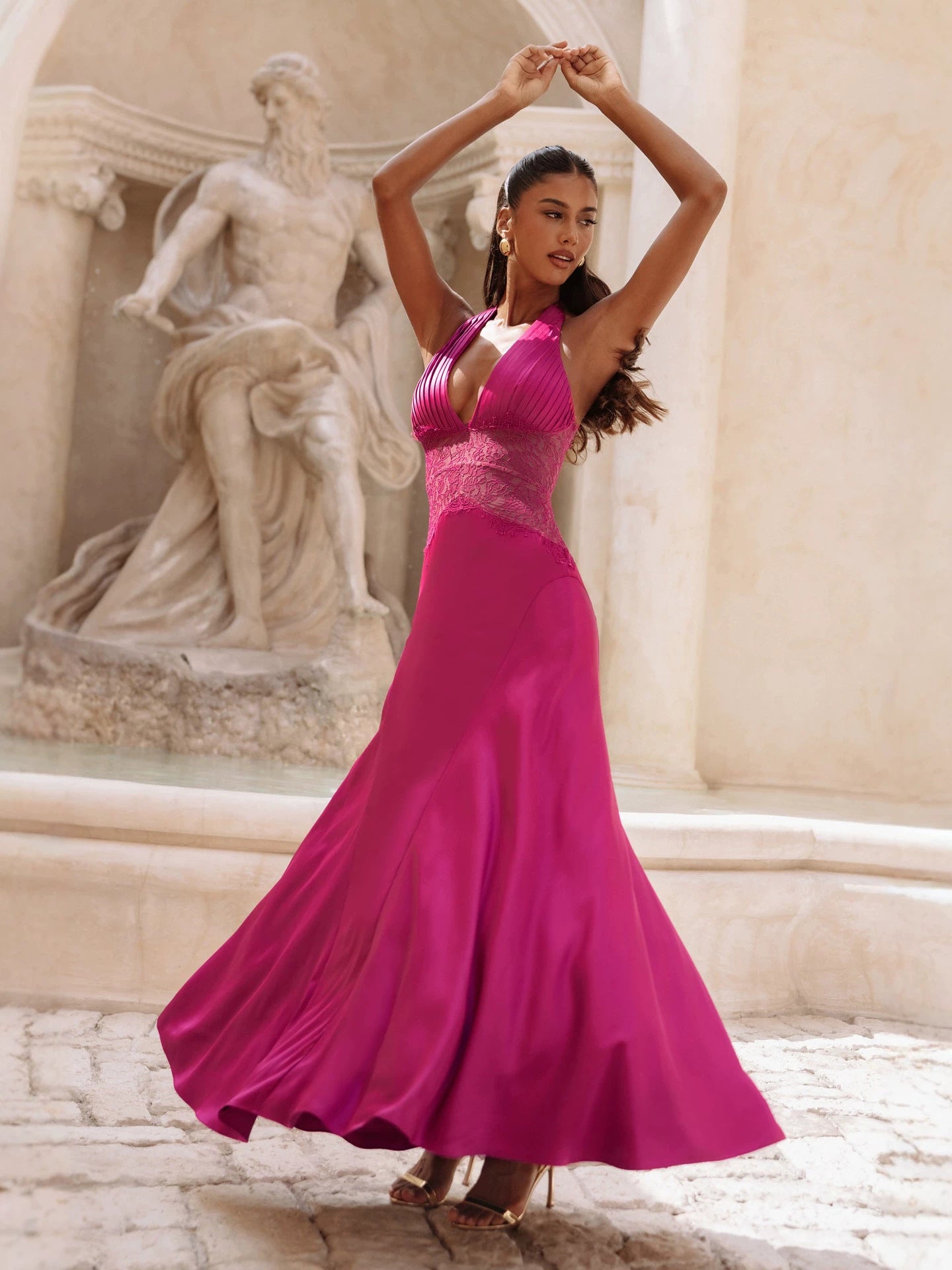 Magenta satin halter gown with the floor length skirt swirling, side view outdoors