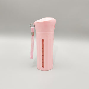 Pink four compartment travel bottle with a wrist strap and ml level window down the side