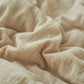 Cream and gray reversible gauze summer quilt folded with maker fabric label showing