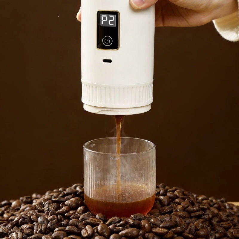 White portable espresso maker extracting a steaming shot over roasted coffee beans