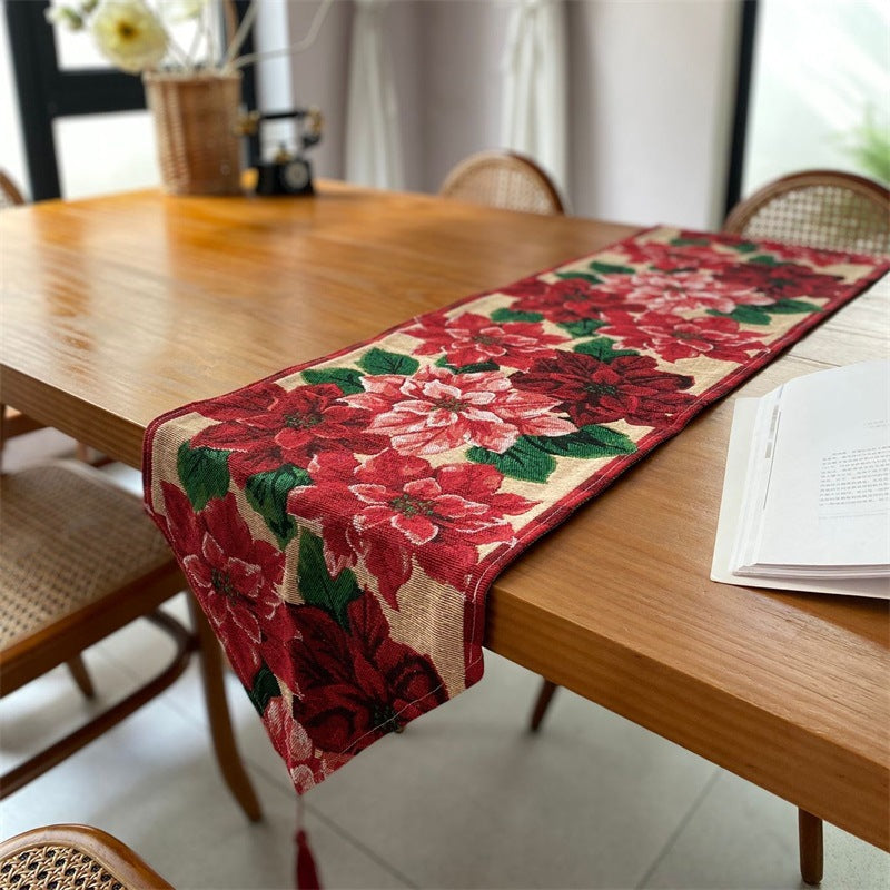 Christmas table runner with red poinsettia pattern and tassel on a wooden table, 33x180 cm option