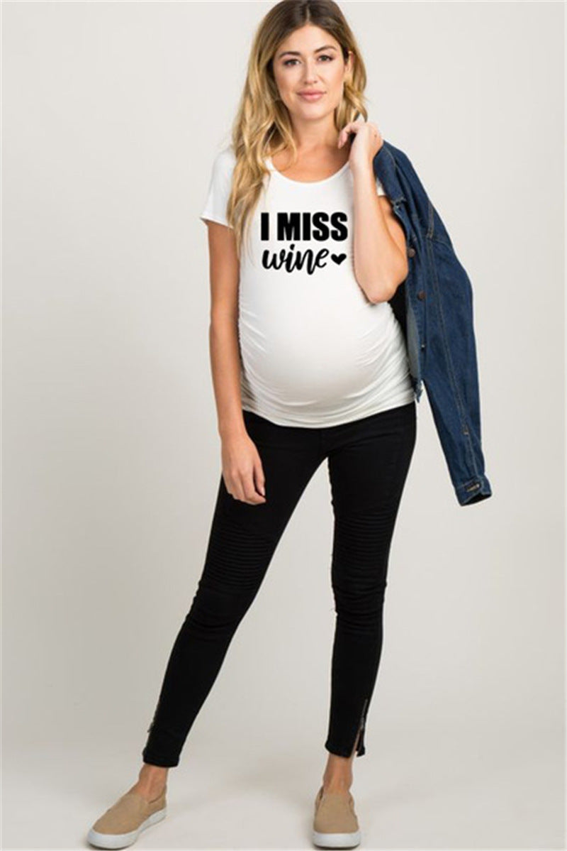 White maternity short sleeve tee with an I Miss Wine print, round neck and side ruching, on a pregnant model