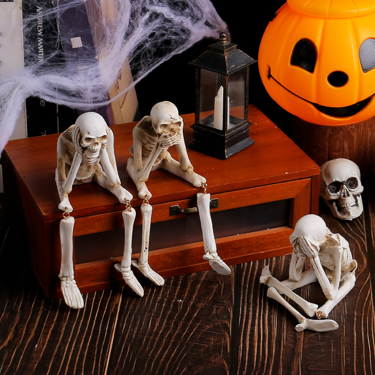 Skeleton shelf sitter figurine with legs dangling over a wooden edge