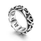 Silver gray scrollwork band ring on a white background showing the engraved gothic lettering inside the band