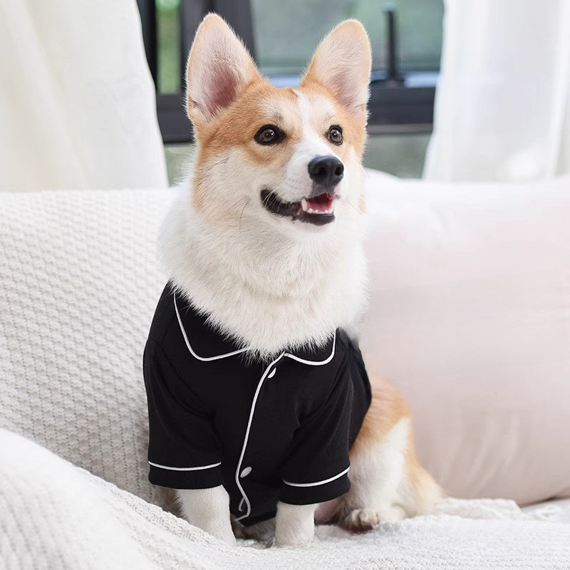 Corgi sitting on a sofa in the black pet pajama shirt with a notched collar and white piping