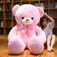Pink plush teddy bear with a striped bow tie sitting in front of a bookshelf with a woman behind it, option Pink 130 cm