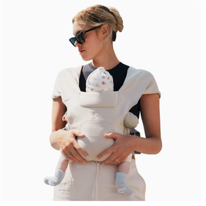 Beige cotton cross-back baby carrier seen from behind showing the X straps over both shoulders