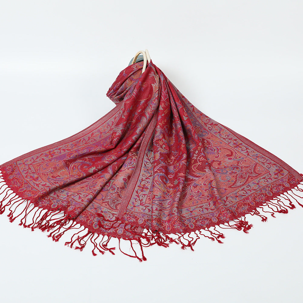 Dark red paisley jacquard scarf spread on a white background with twisted dark red tassel fringe