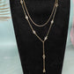 Gold rhinestone station necklace with a Y drop shown on a black bust display
