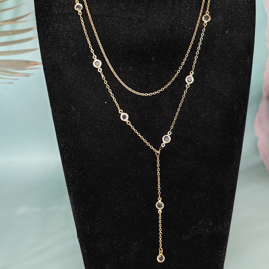 Gold rhinestone station necklace with a Y drop shown on a black bust display