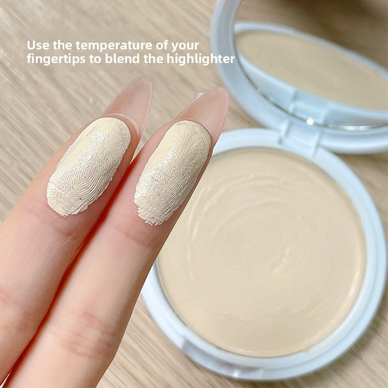 Fingertips blending Gellas cream highlighter beside the open compact