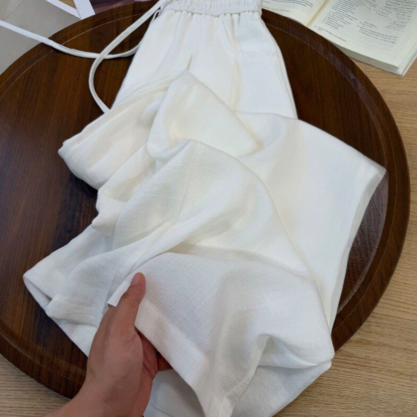 Light blue cotton linen summer pants draped over a wooden tray edge