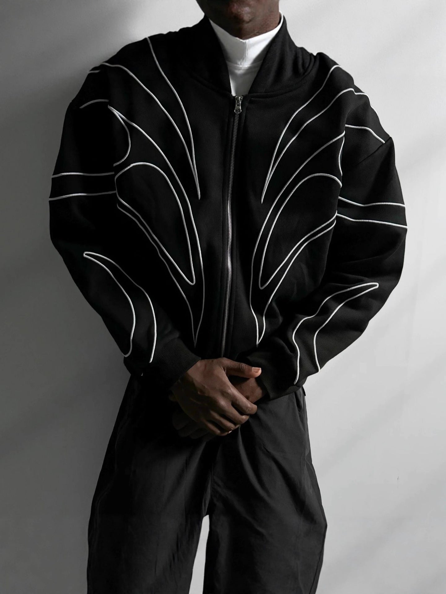 Front view of a black embroidered zip up hoodie laid on a bench