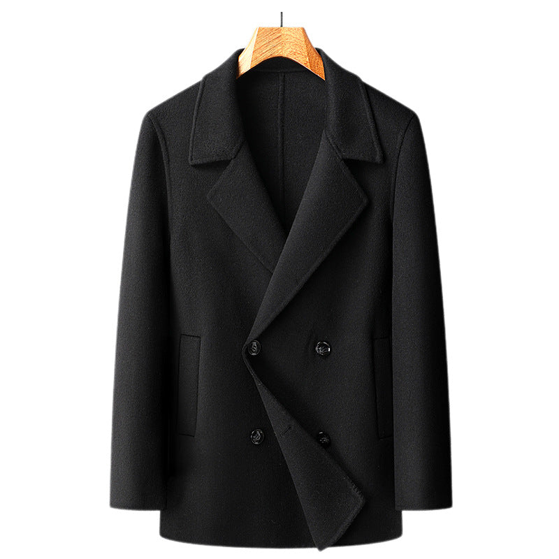 Black double breasted wool overcoat on a wooden hanger, front view of the buttoned closure