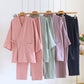 Pink, green, purple and navy kimono pajama sets hanging on hangers with wrap tops, side ties and patch pockets