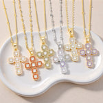 Gold tone cubic zirconia cross pendant necklaces shown side by side on a ceramic tray