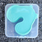 Stack of four mint green bear shaped skin pads inside a clear plastic storage box with clip lid