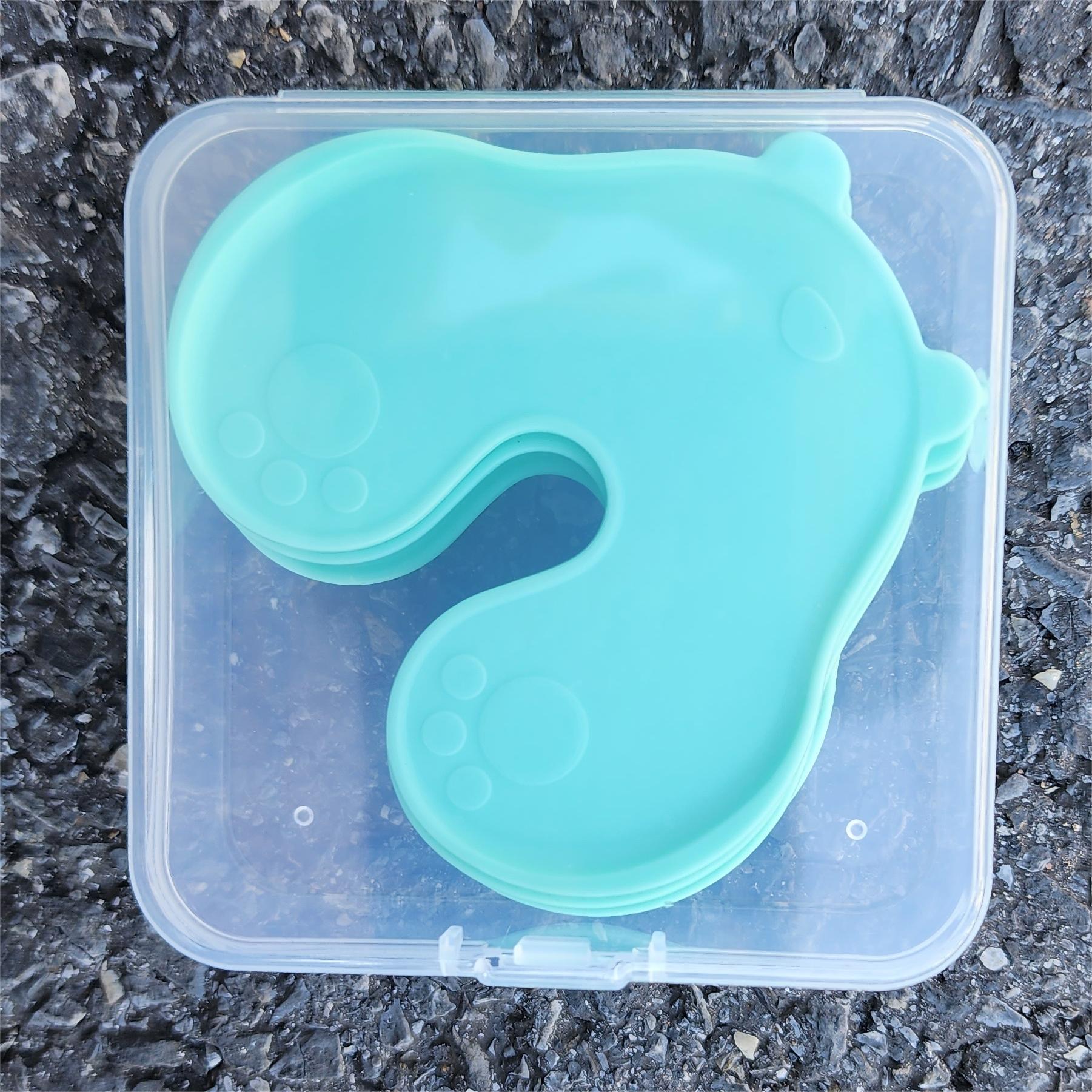 Stack of four mint green bear shaped skin pads inside a clear plastic storage box with clip lid