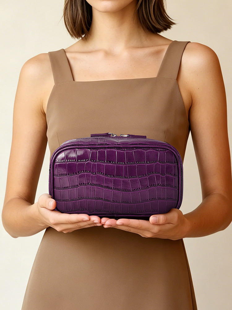 Woman holding a purple crocodile pattern cosmetic bag with both hands in front of her