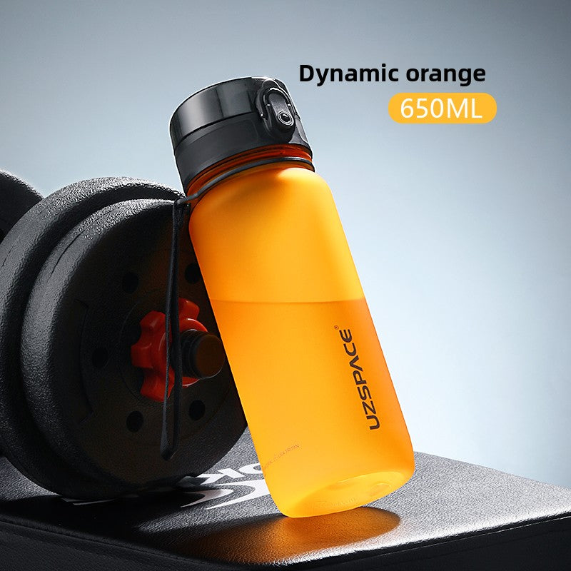 Orange sports water bottle labelled dynamic orange 650 ml beside a dumbbell