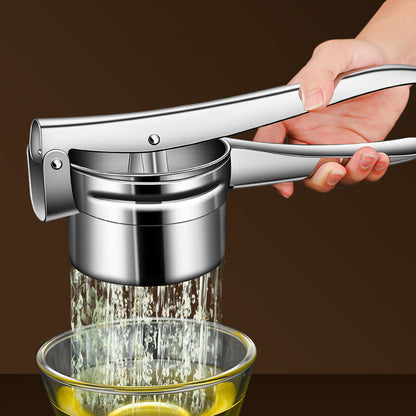 Stainless steel lever juice press held over a glass bowl, juice running from the perforated cup