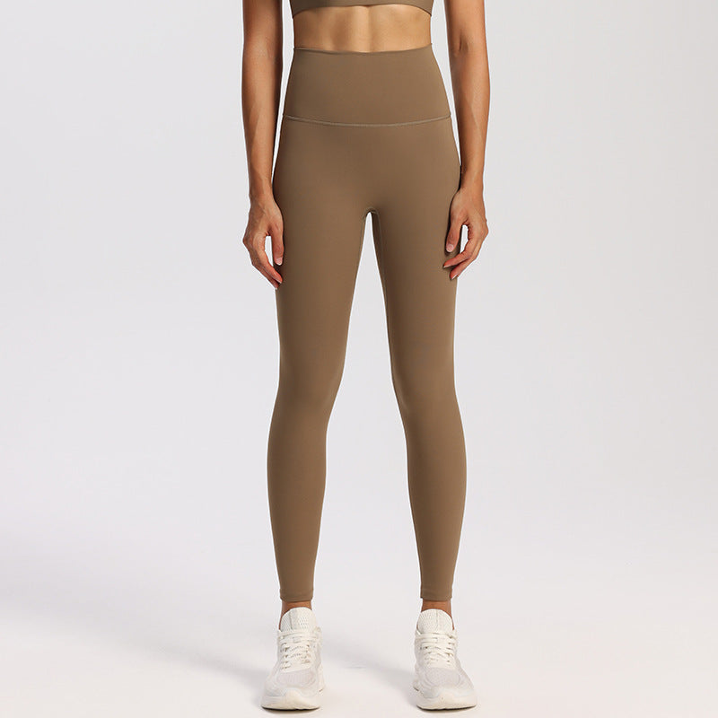 Wide high-rise waistband yoga leggings, nylon spandex knit, worn against a studio wall