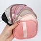 Hand holding a fan of reusable makeup remover pads in pink, gray and mauve shades