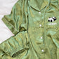 Green pajama shirt sleeve with white piping beside the elastic shorts hem and front button row