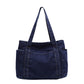 Dark blue denim shoulder tote shown from the back on a white background, twin straps and end patch pockets