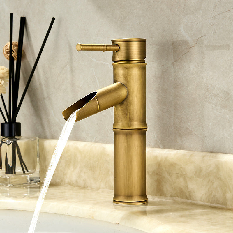 Antique copper bamboo basin faucet with a lever handle running water on a marble countertop