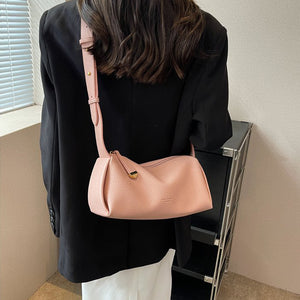 Pink pebbled vegan leather barrel shoulder bag worn crossbody with a long adjustable strap