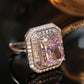Pink radiant stone ring framed by baguette and round clear accents in an octagonal halo, dark styled scene
