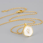 White marbled enamel gold plated cross pendant on a full gold tone cable chain with lobster clasp, flat lay