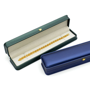 Dark green crown clasp necklace box open with a gold bracelet inside, beside a closed navy box