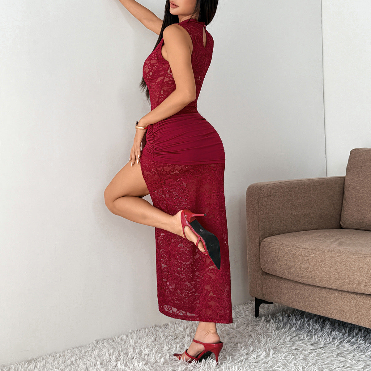 Wine red lace maxi dress in a side pose showing the ruched hip panel and high slit, with red heels