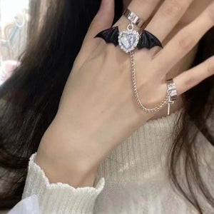 Bat wing ring worn on hand, clear heart crystal centerpiece with silver chain draping to a cross