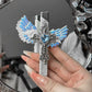Hand holding the angel wings cross lighter upright before a mirror, white wings and blue heart stone visible