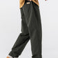 Green straight leg cotton pants seen mid stride with white sneakers and a mustard sweater