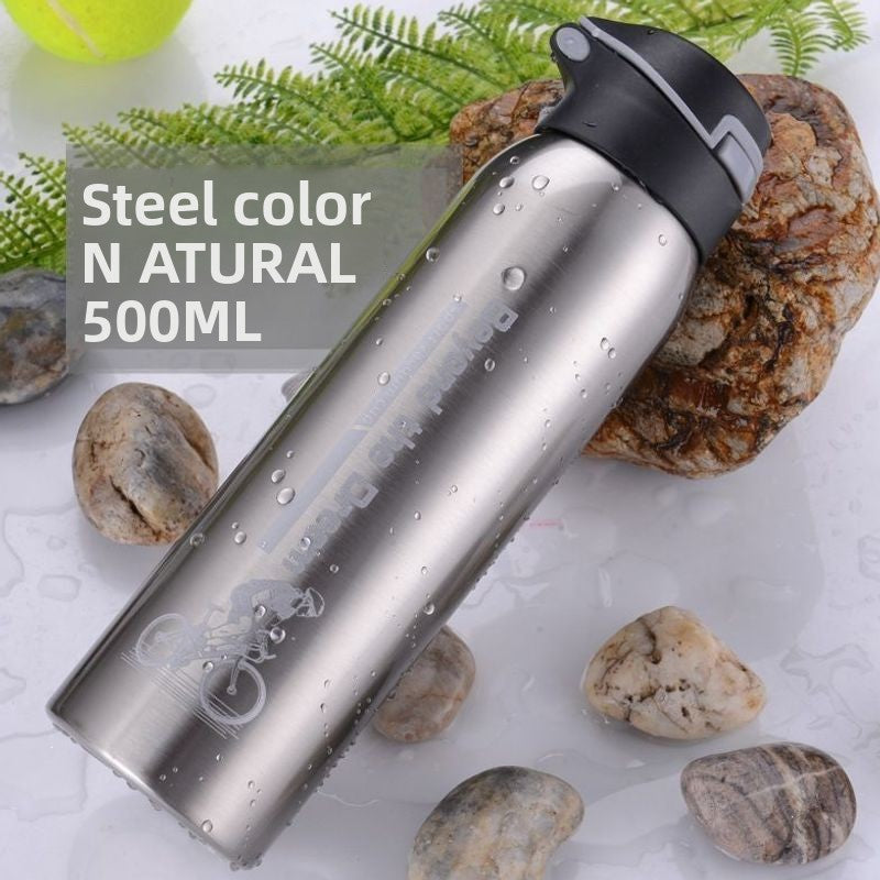 Natural silver stainless steel sports bottle with black flip lid lying on pebbles with water drops, silver option