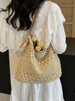 Beige woven straw shoulder tote bag with colorful boho strap carried on the back