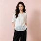 Semi sheer white embroidered shirt worn untucked over black trousers